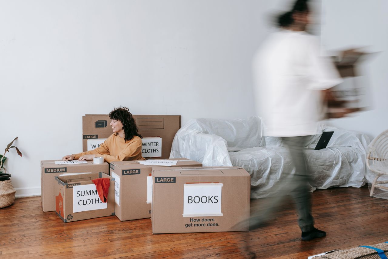 hero-img-02 A couple carefully packing labeled boxes in a minimalist living room as they get ready for moving day.